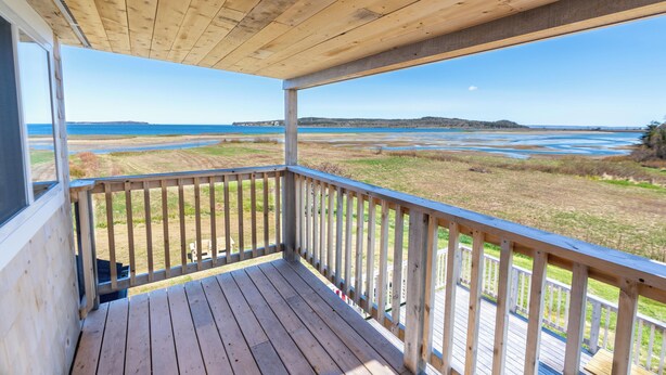 Une terrasse en bois offrant une vue sur une plage et une île lointaine.