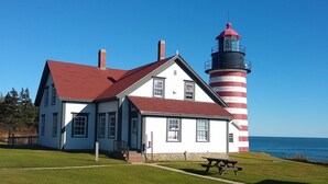Un bâtiment blanc avec un toit rouge et un phare aux rayures rouges et blanches.