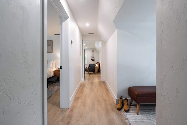 A hallway with wooden flooring, a bench, and a guitar in the background. - Rhythm at The Key | 1mi to UF & DT • Full Kitchen (Gainesville)