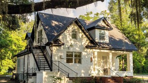 A two-story house with a white exterior, a black roof, and a front porch.