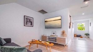 Un salon moderne avec un canapé, une table basse, un téléviseur et une vue sur un lac.
