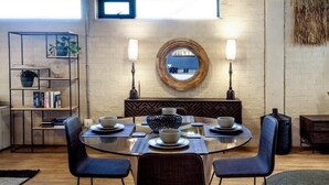 Un comedor con una mesa redonda, sillas y un espejo decorativo en el centro.