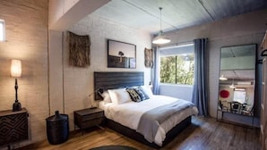 Un dormitorio moderno con una cama grande, una mesita de noche, una lámpara y una ventana con cortinas.