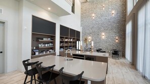 A spacious kitchen with a central island, built-in shelves, and a stone accent wall. - Landing | Incredible 1BD, Courtyard, Pool (Austin)