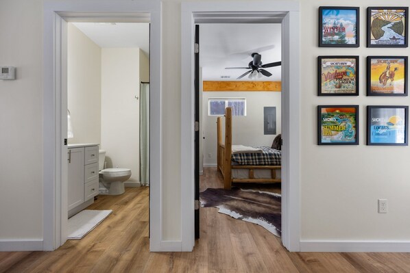 A bedroom with a bed, a ceiling fan, and a wall with framed posters. - Hilltop Hideaway located moments away from Shanty Creek & Torch Lake (Bellaire)