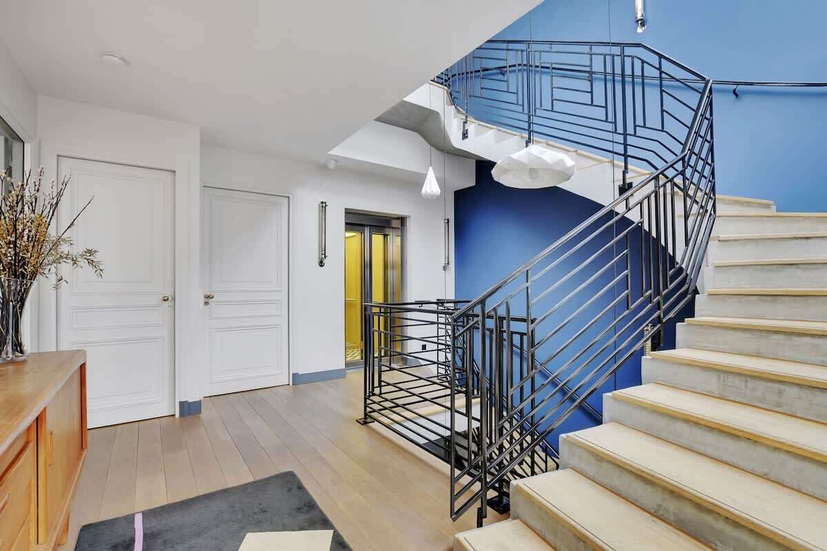 Een modern interieur met een trap, houten vloeren en een blauwe accentmuur.