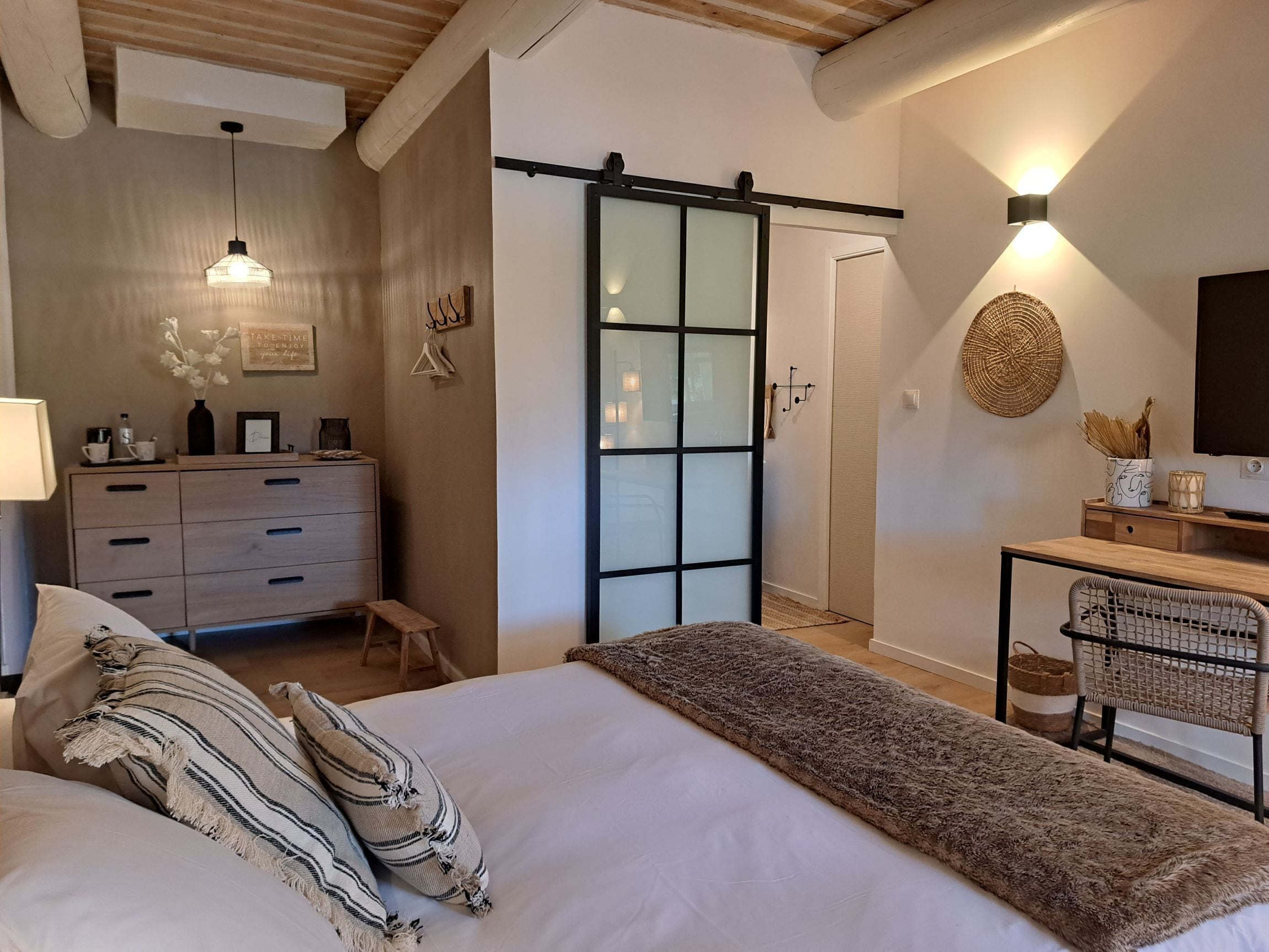 Une chambre à coucher comprenant un lit, une commode, un bureau et une porte coulissante.
