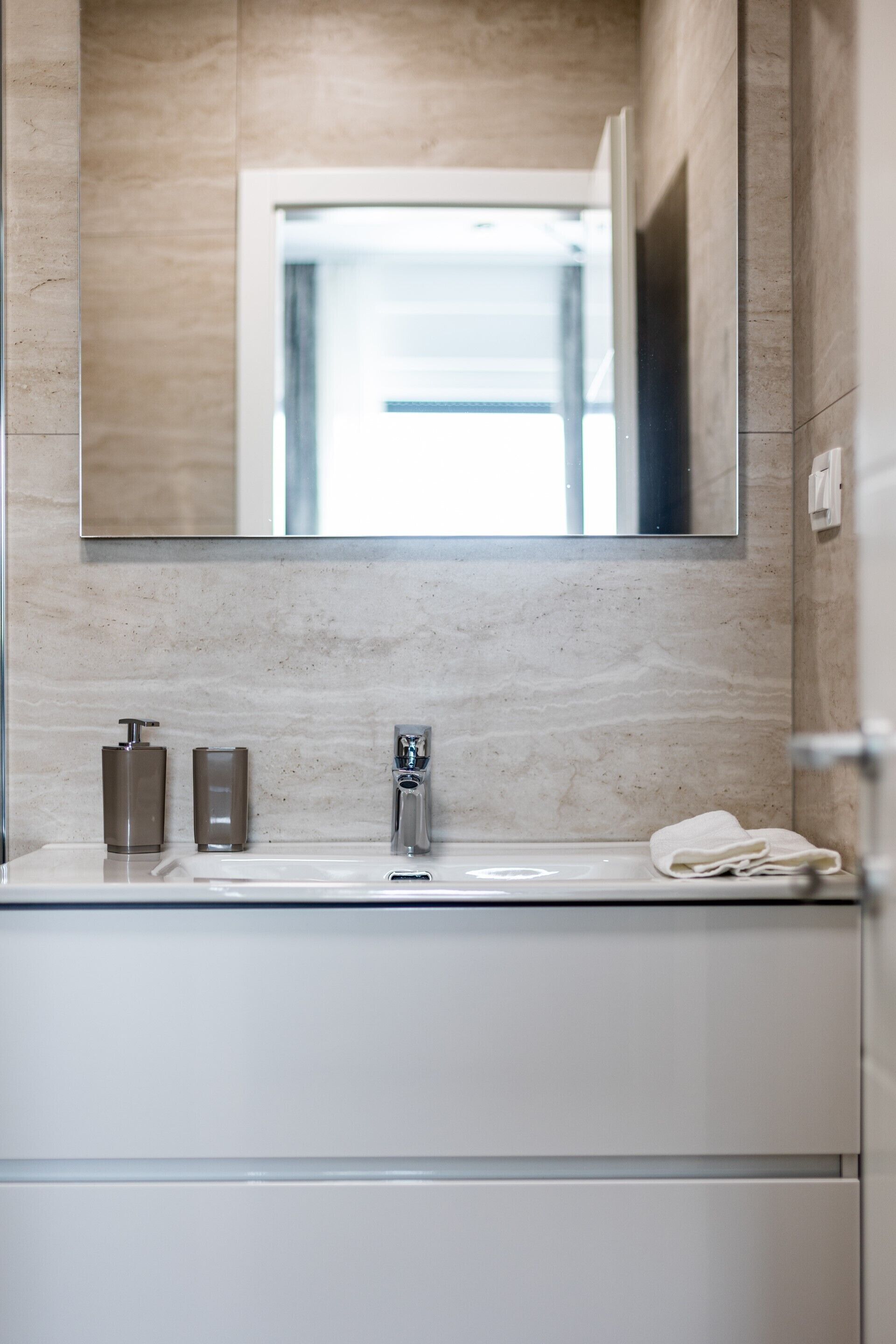 Une salle de bain moderne avec un lavabo en marbre, un grand miroir et une serviette posée sur le comptoir.
