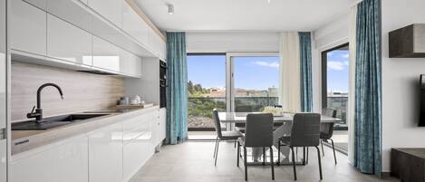 A modern kitchen with white cabinets, a wooden countertop, and a dining area with a table and chairs.