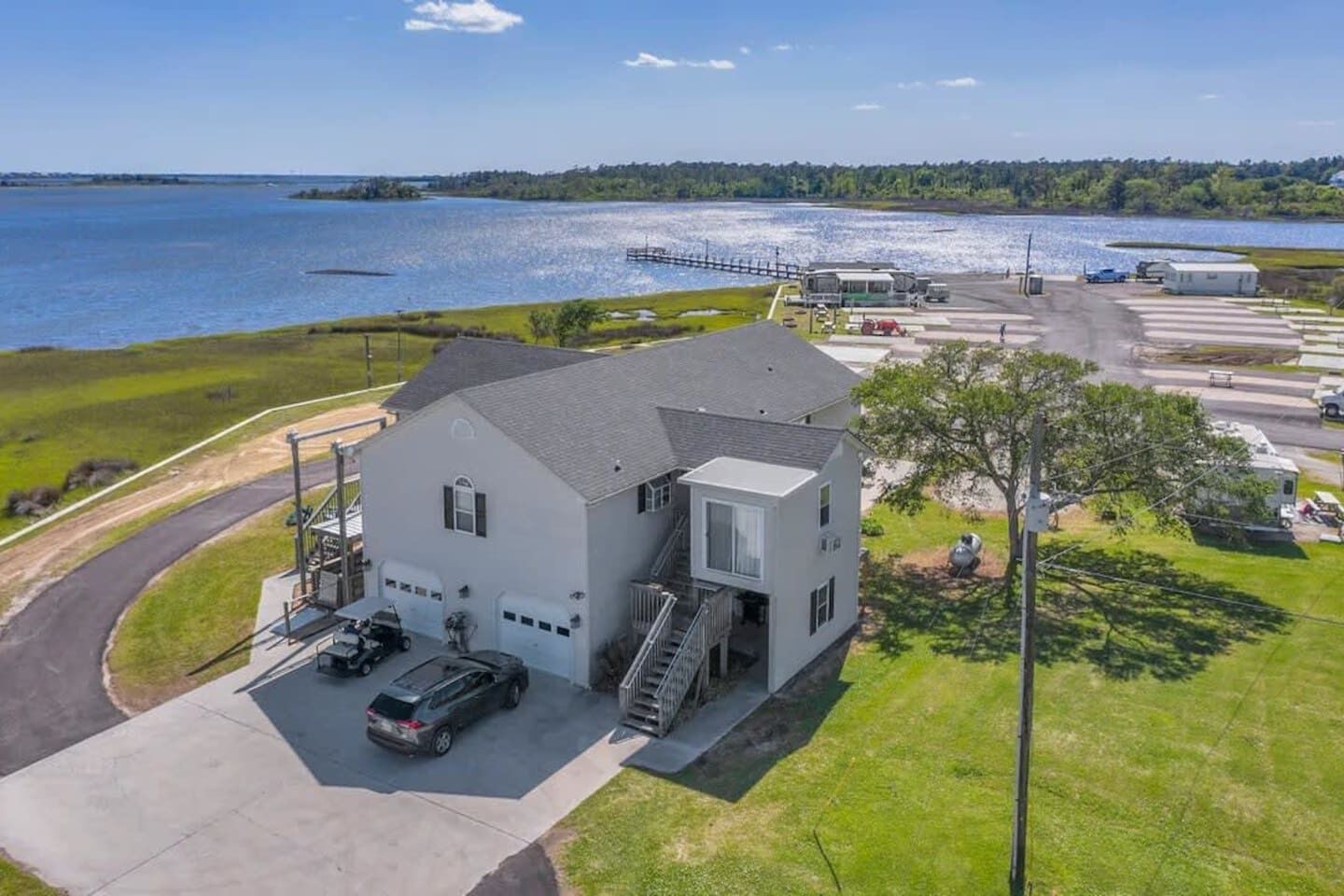 Uma casa de dois andares com garagem, entrada por rampa e um píer para barcos.