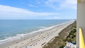 Een strand met een lange zandvlakte, enkele parasols en wat mensen.