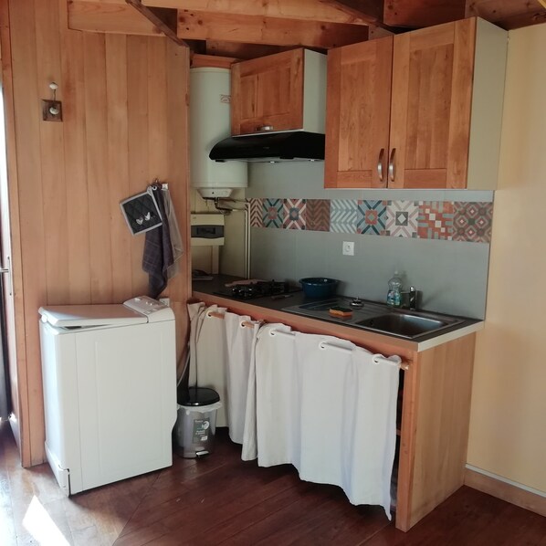 A compact kitchen with wooden cabinets, a built-in stove, and a small sink.