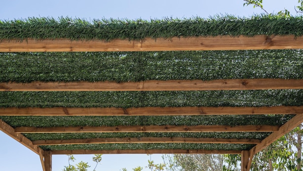 An outdoor dining area with a pergola covered in greenery, stone flooring, and a view of trees and hills. - Casa Rosa: Long-term Living & Workspace (Valencia)