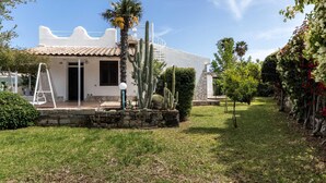 A white building with a tiled roof, a stone staircase, and a cactus garden. - Villa Karibu in Cicirata (Avola)
