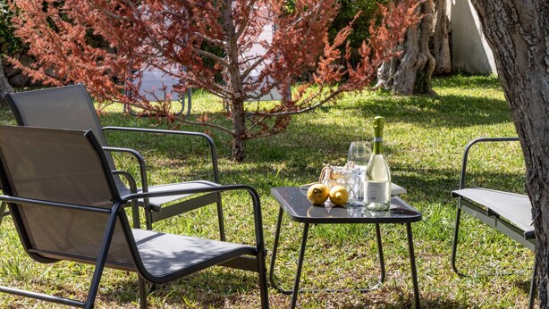 An outdoor seating area with metal chairs and a small table, a bottle of wine, and lemons. - Villa Karibu in Cicirata (Avola)