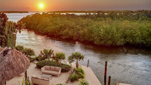 A riverside patio with outdoor seating and a thatched umbrella. - Isla Guava: Boutique Resort, FREE Boat Dockage Sept-Oct Only! (Islamorada)