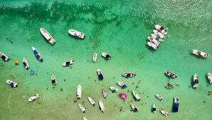 An aerial view of a beach with numerous boats and people scattered across the shallow waters. - Isla Key Lime: Boutique Resort, FREE Boat Dockage Sept-Oct Only! (Islamorada)