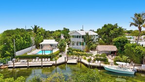 A resort with a swimming pool, a boat dock, and a thatched-roof structure. - Isla Key Lime: Boutique Resort, FREE Boat Dockage Sept-Oct Only! (Islamorada)