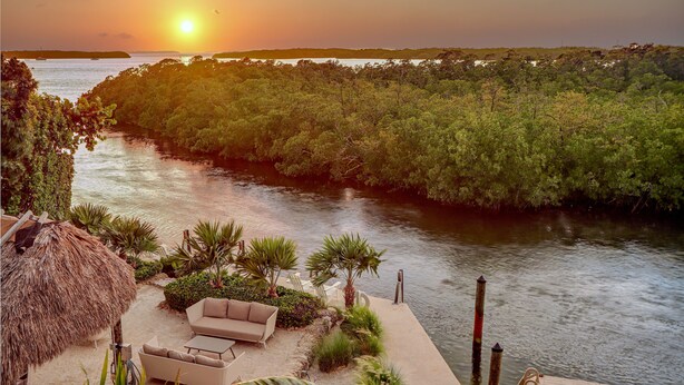 A riverside patio with outdoor seating and a thatched umbrella. - Isla Key Lime: Boutique Resort, FREE Boat Dockage Sept-Oct Only! (Islamorada)