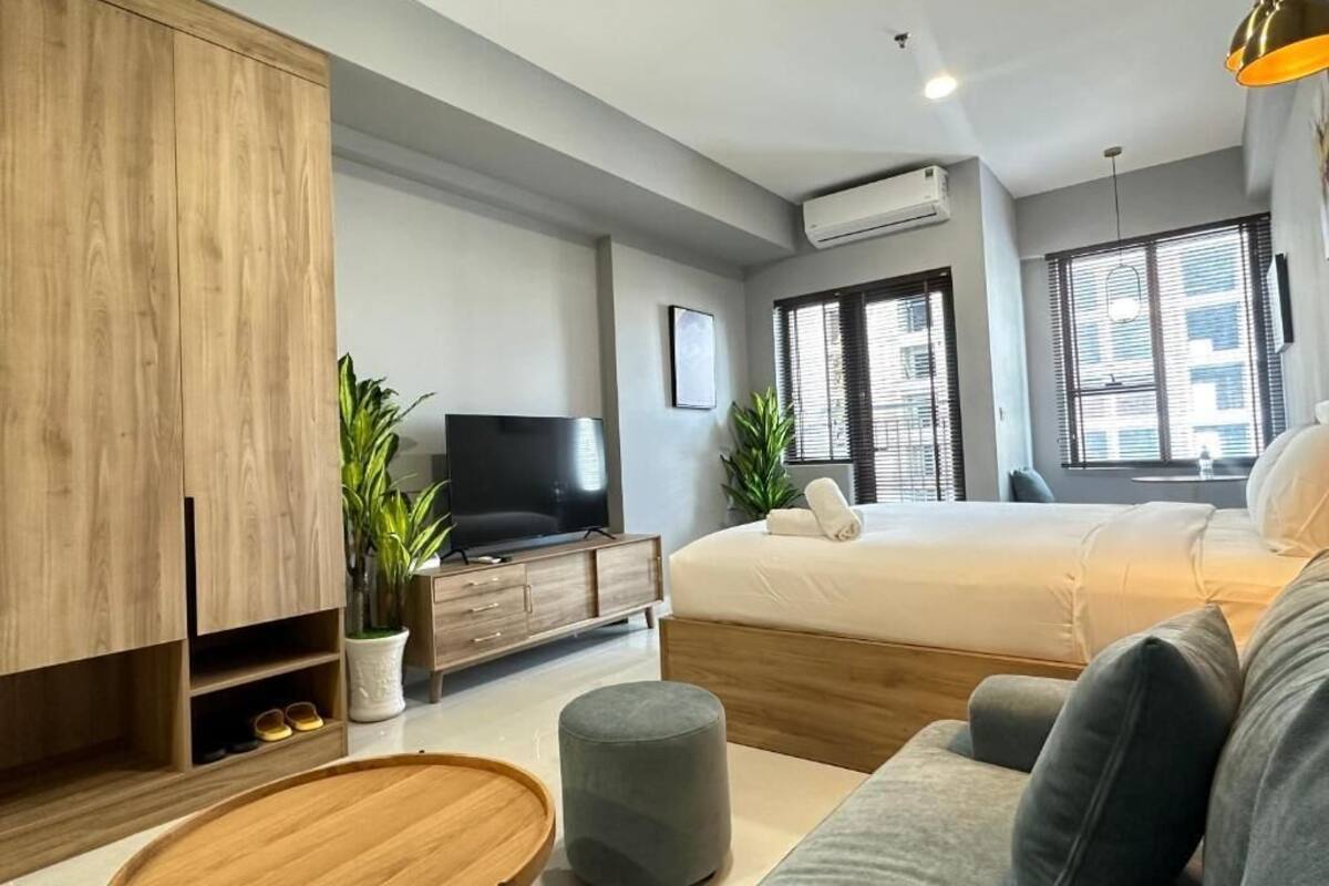 Een moderne slaapkamer met een bed, een televisie, een kledingkast en een zithoekje.