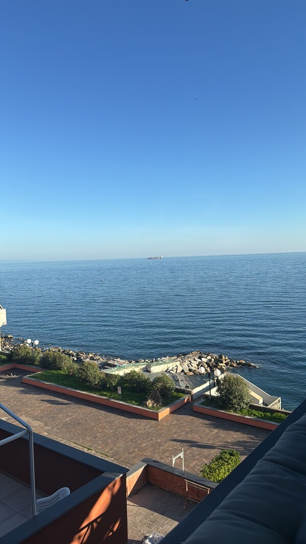 Une vue sur la mer depuis un balcon, avec un ciel dégagé.