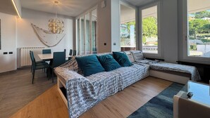 A modern bedroom with a large bed, a dining area, and a view of the outdoors. - La Soluzione Perfetta (Arenzano)