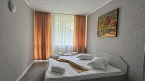 A modern hotel room with a single bed, a painting on the wall, and a window with curtains. - Legacy Hotel (Eforie)