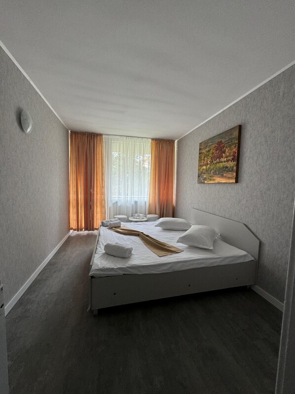 Una habitación de hotel moderna con una cama individual, un cuadro en la pared y una ventana con cortinas.