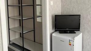 A walk-in closet with open shelves and a flat-screen TV on a small white appliance. - Legacy Hotel (Eforie)