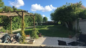A garden with a wooden pergola, outdoor seating, and a well-maintained lawn. - La Maison Glycine. A charming 3 bedroom cottage set in beautiful countryside  (La Villedieu)