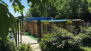 A pathway leading to a building with a blue roof, surrounded by greenery and a fence. - La Maison Glycine. A charming 3 bedroom cottage set in beautiful countryside  (La Villedieu)