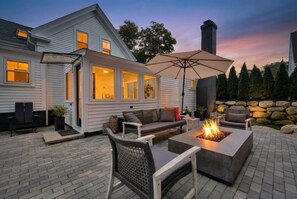 Une terrasse dotée d’un foyer extérieur, de mobilier de jardin et d’un mur en pierre.