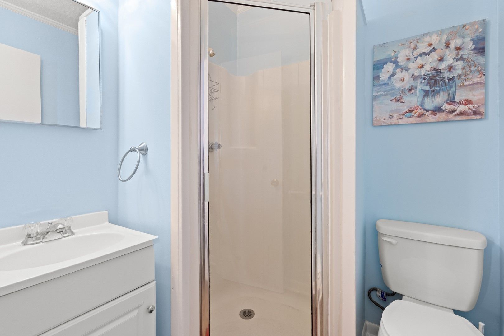 Un baño con ducha, inodoro y lavamanos con espejo.