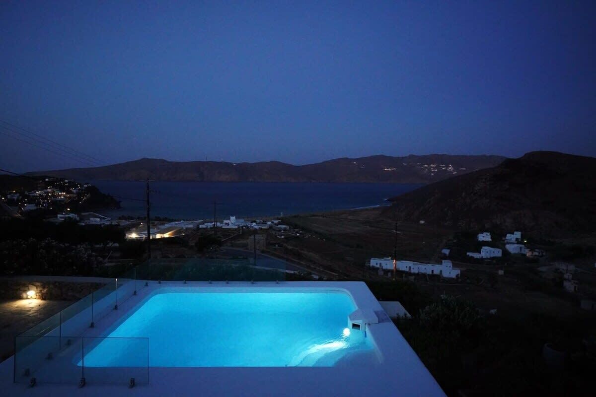 Piscina com vista para paisagem costeira ao entardecer.