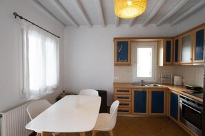 Eine kleine Küche mit weißem Tisch, Holzschränken und einer Pendelleuchte.