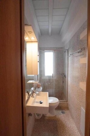 Ein kleines Badezimmer mit Dusche, Toilette und Waschbecken.