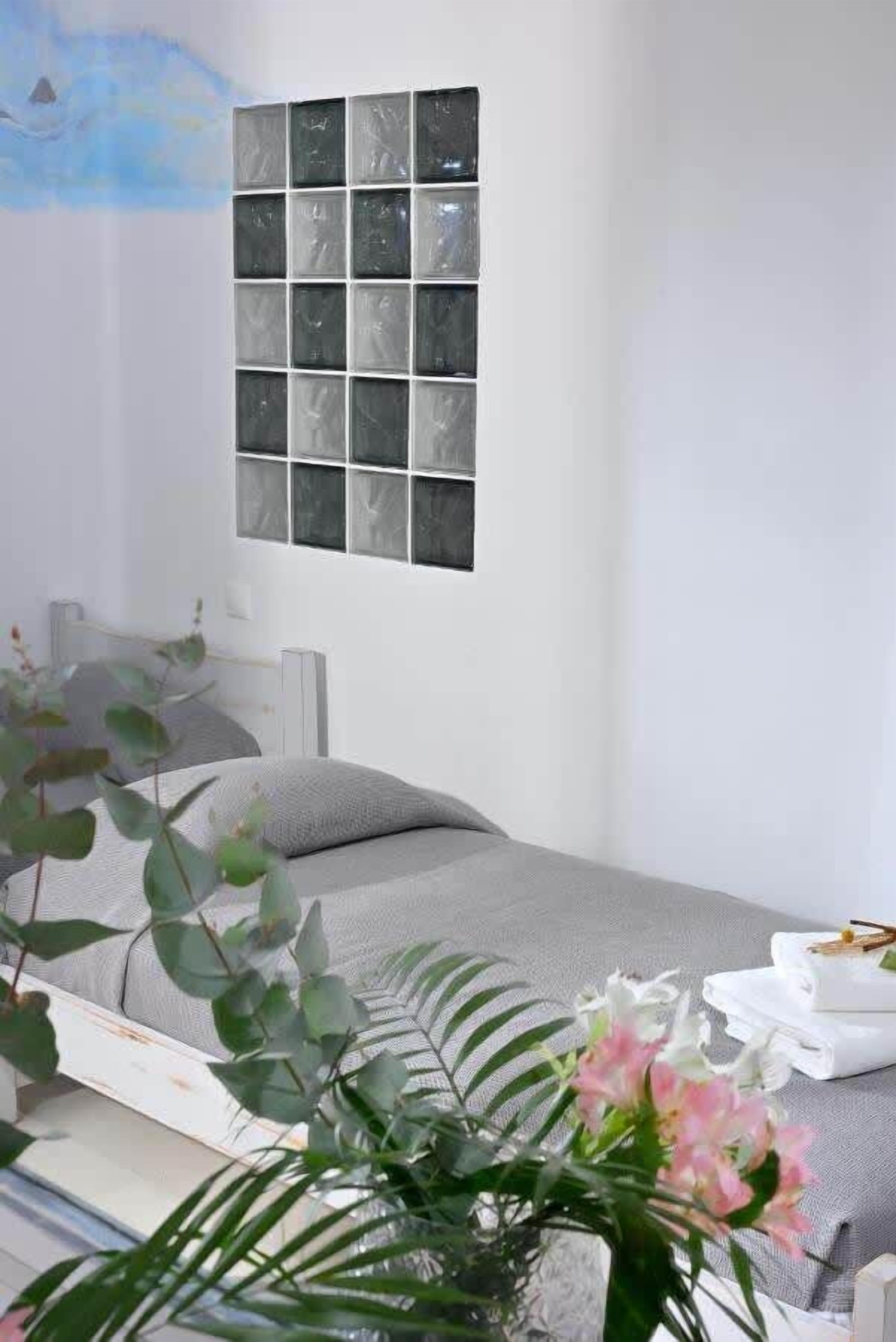 A modern bedroom with a bed, a wall-mounted artwork, and a bedside table with a lamp.