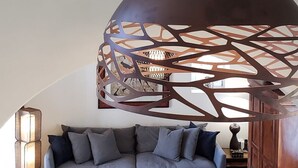 Un soggiorno moderno con un divano grigio, un tavolino da caffè e un pannello decorativo in metallo.