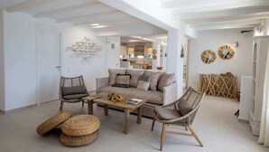 Un salon comprenant un canapé, deux fauteuils, une table basse et un élément décoratif mural.