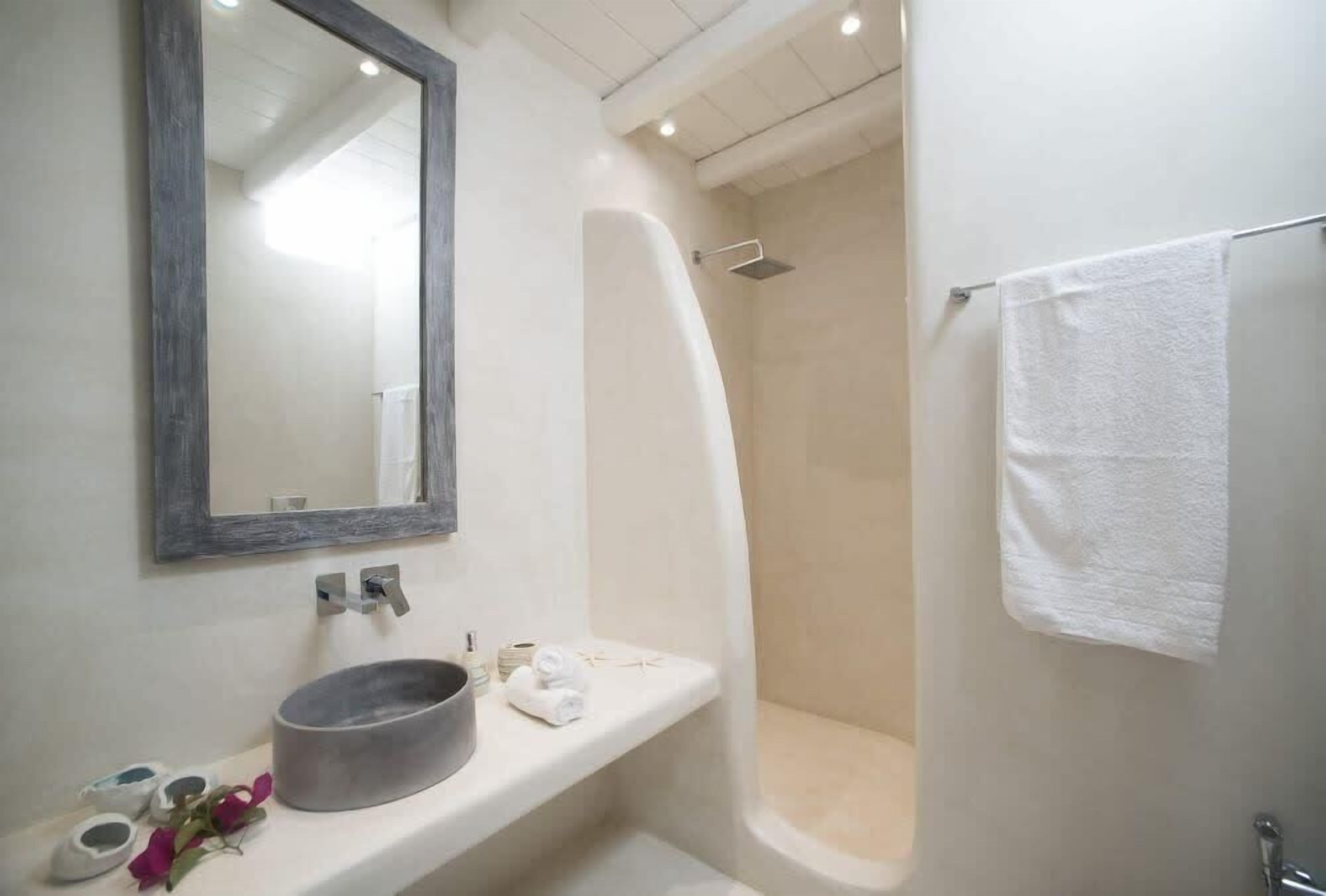 Un bagno moderno con uno specchio grande, un lavabo rotondo, una doccia e un porta asciugamani.