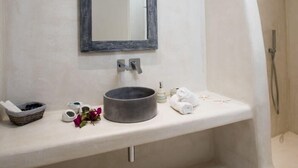 Un baño moderno con un espejo grande, un lavabo redondo y una ducha.