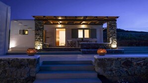A modern house with a stone facade, a covered patio, and a pool area. - Mykonian Luxury Light Blue Villa with Private Pool (Mykonos)