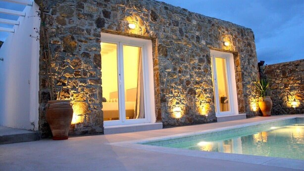 A stone building with a pool, large windows, and outdoor lighting. - Mykonian Luxury Light Blue Villa with Private Pool (Mykonos)