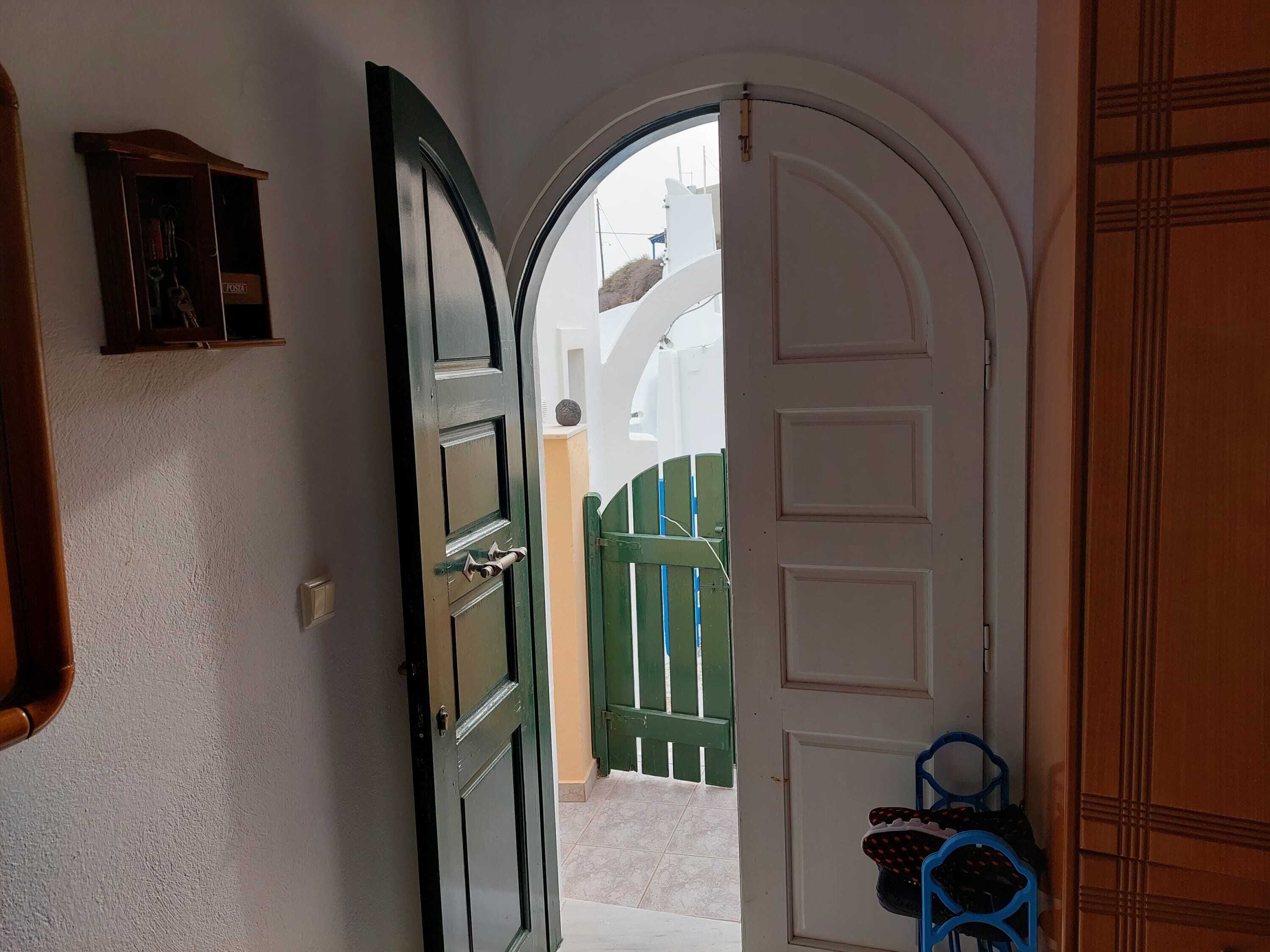 A hallway with a white door leading to an outdoor area with a green gate.