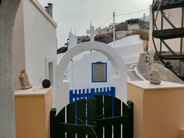 A white building with a blue window and a green gate.