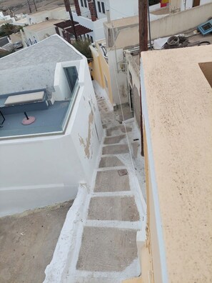 A narrow stairway leading to a rooftop terrace with a small seating area.