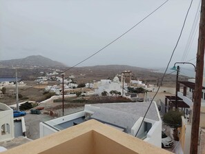 A coastal town with white buildings, a mountain in the background, and a view of the sea.