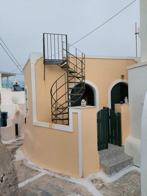 A building with a spiral staircase, a small balcony, and a gate.