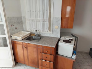 A kitchen with a granite countertop, a stainless steel sink, wooden cabinets, and a white stove.