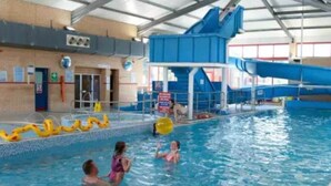 An indoor swimming pool with a blue water slide and inflatable toys.